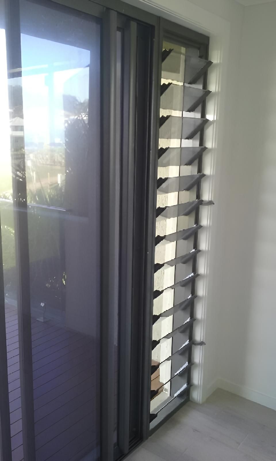 A Room with A Sliding Glass Door and A Window with Shutters on It — Grainger Windows & Doors in Alstonville, NSW