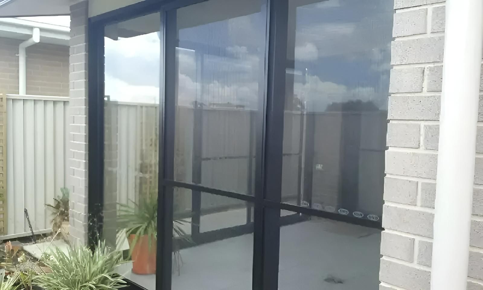 A Sliding Glass Door Leading to A Patio in A House — Grainger Windows & Doors in Ballina, NSW