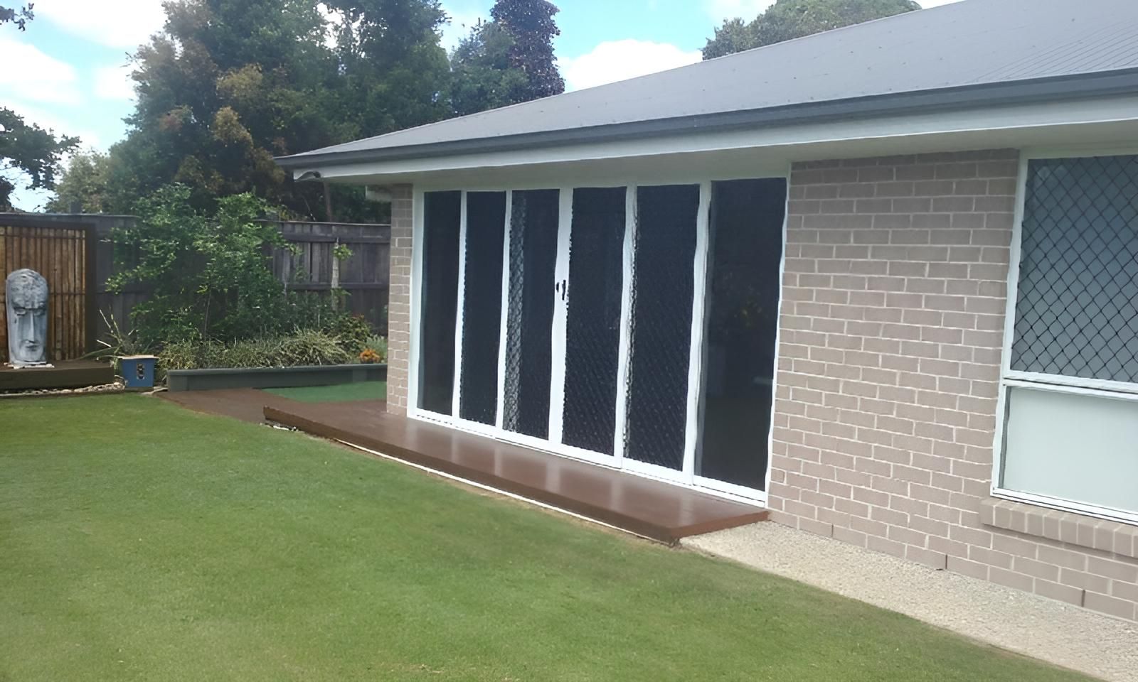 A Brick House with A Lawn in Front of It — Grainger Windows & Doors in Wollongbar, NSW