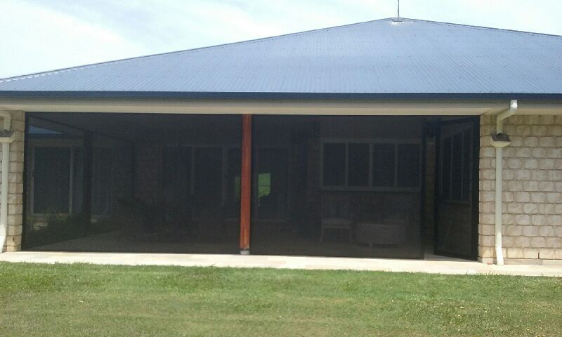 A House with A Screened in Porch and A Lawn in Front of It — Grainger Windows & Doors in Ballina, NSW