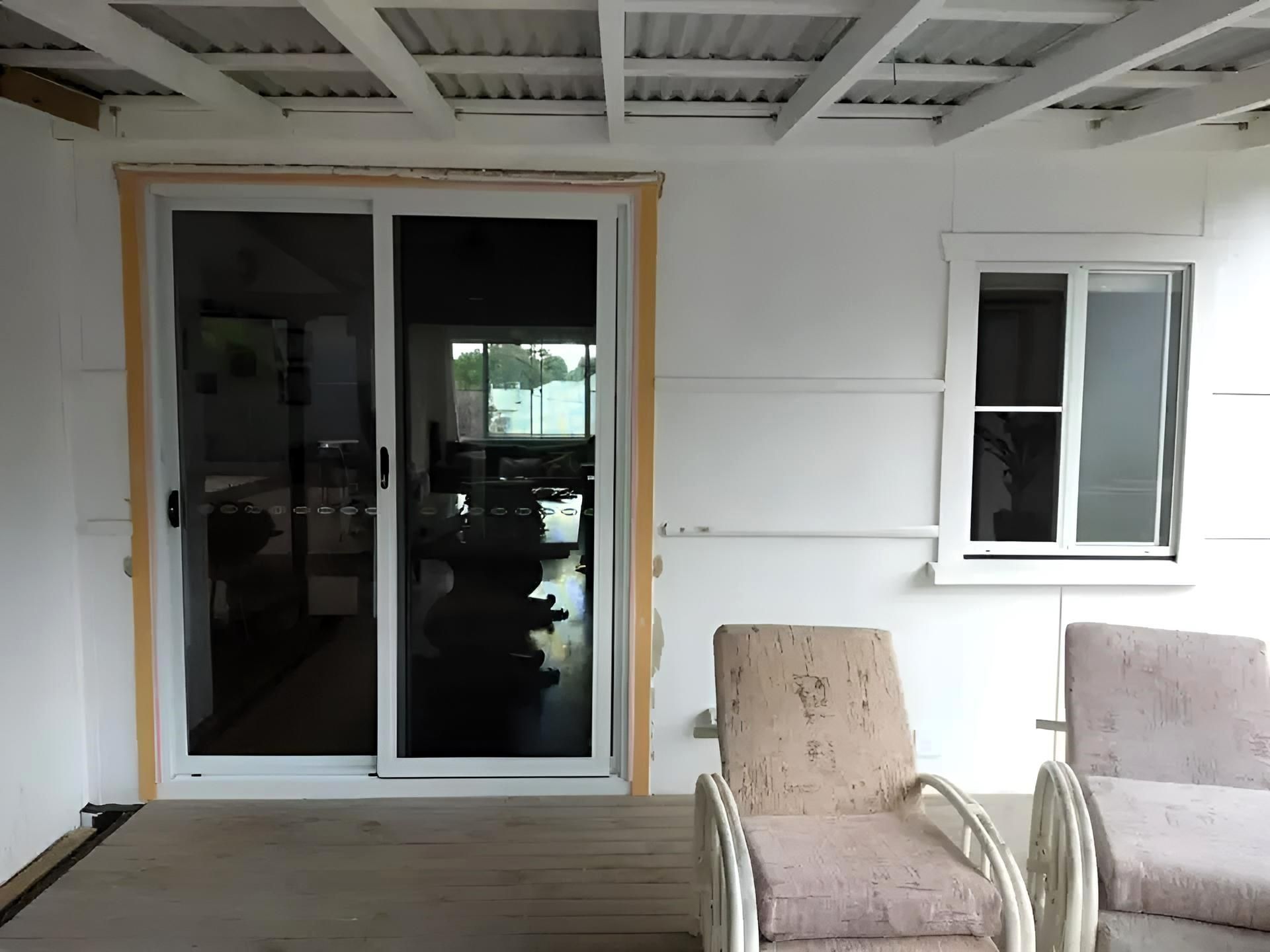 A Patio with Two Chairs and A Sliding Glass Door — Grainger Windows & Doors in Ballina, NSW
