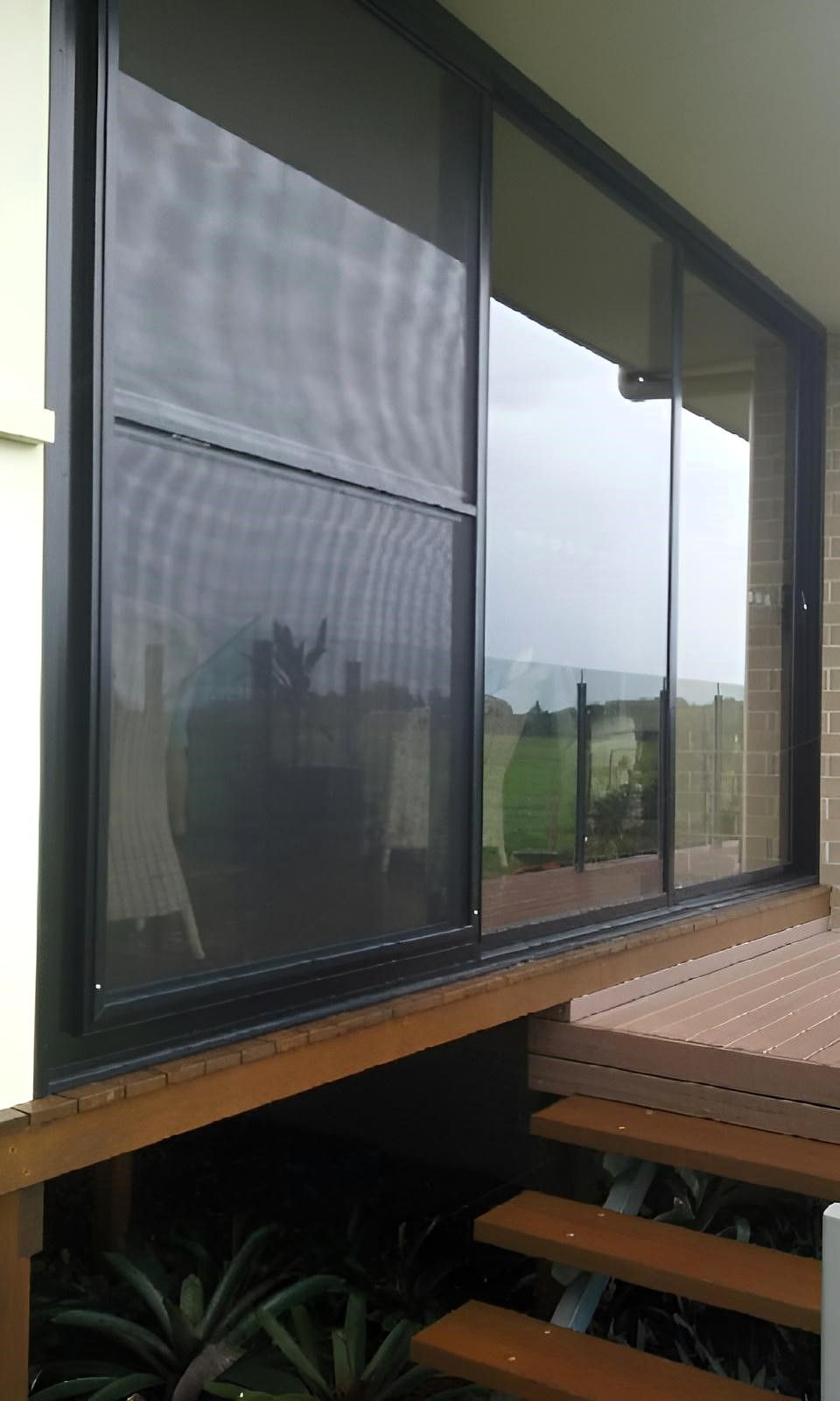 A Large Window on The Side of A House with A Wooden Deck — Grainger Windows & Doors in Wardell, NSW