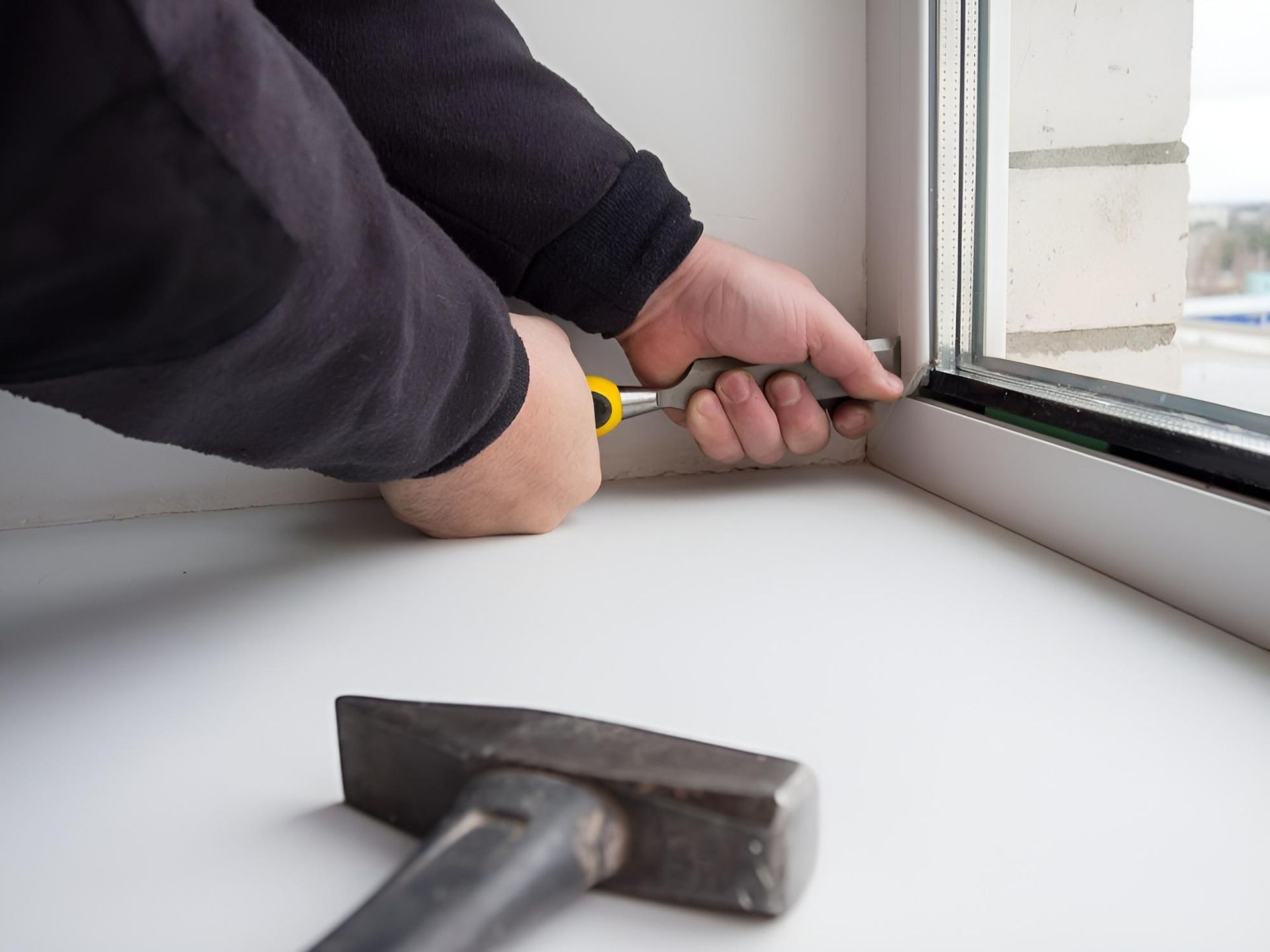 A Man Is Fixing a Window with A Hammer and A Screwdriver — Grainger Windows & Doors in Ballina, NSW