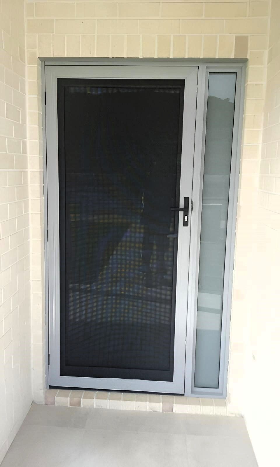 A Door with A Screen on It Is Sitting on A Brick Wall — Grainger Windows & Doors in Ballina, NSW