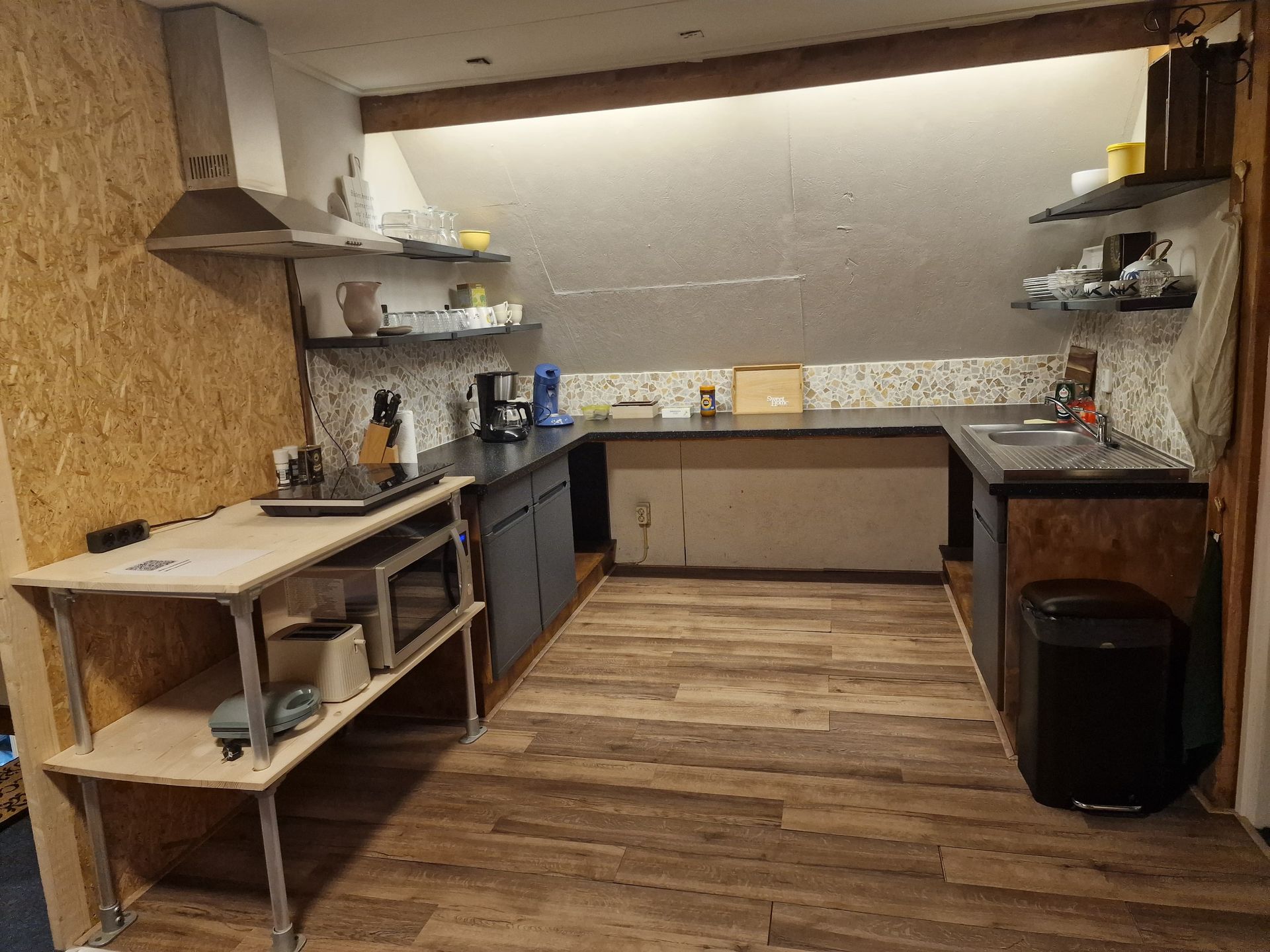 Kleine, minimalistische keuken met houten aanrechtbladen, open planken en een houten lambrisering.