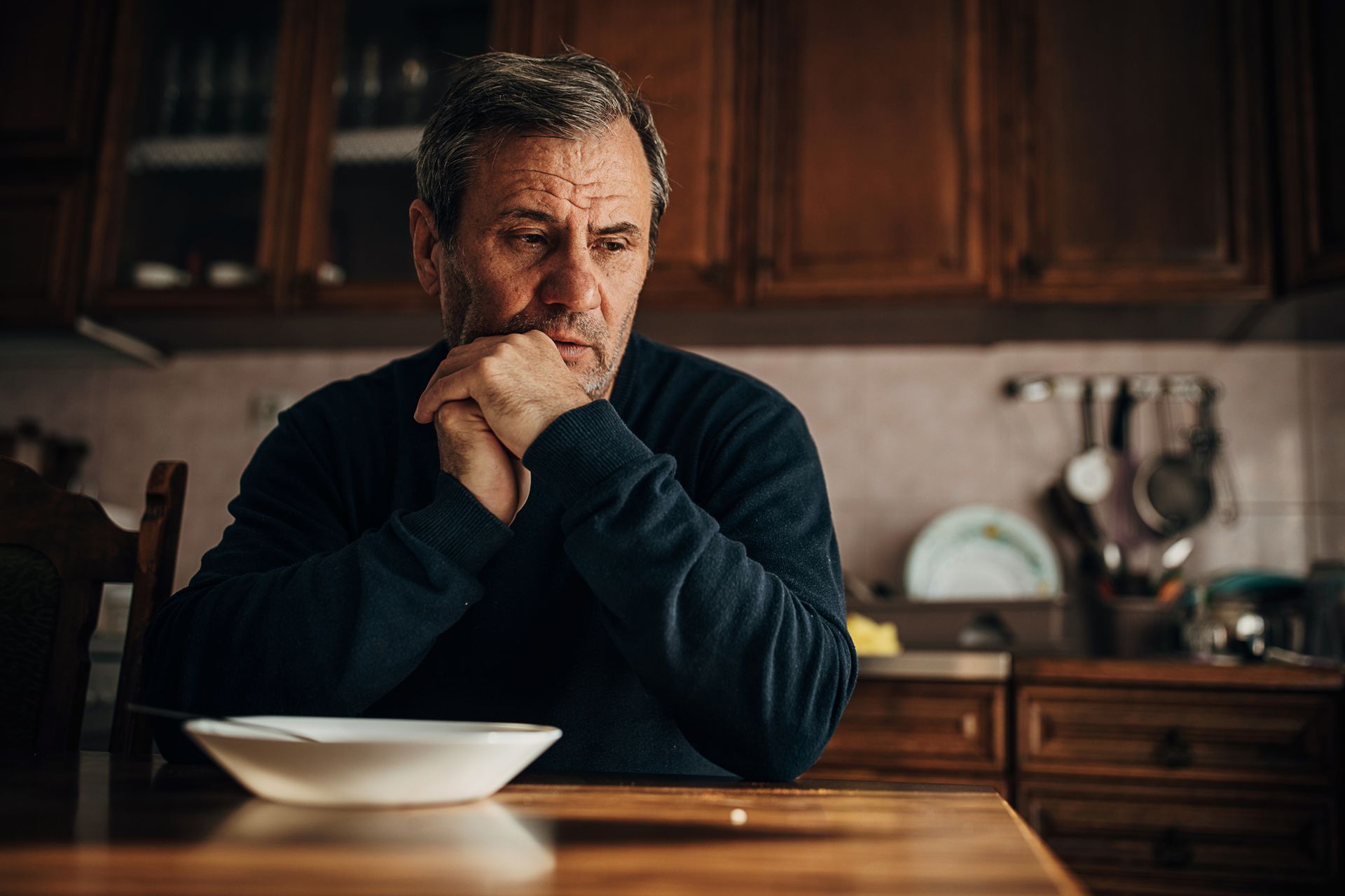 An older man is sitting at a table with a bowl of food.