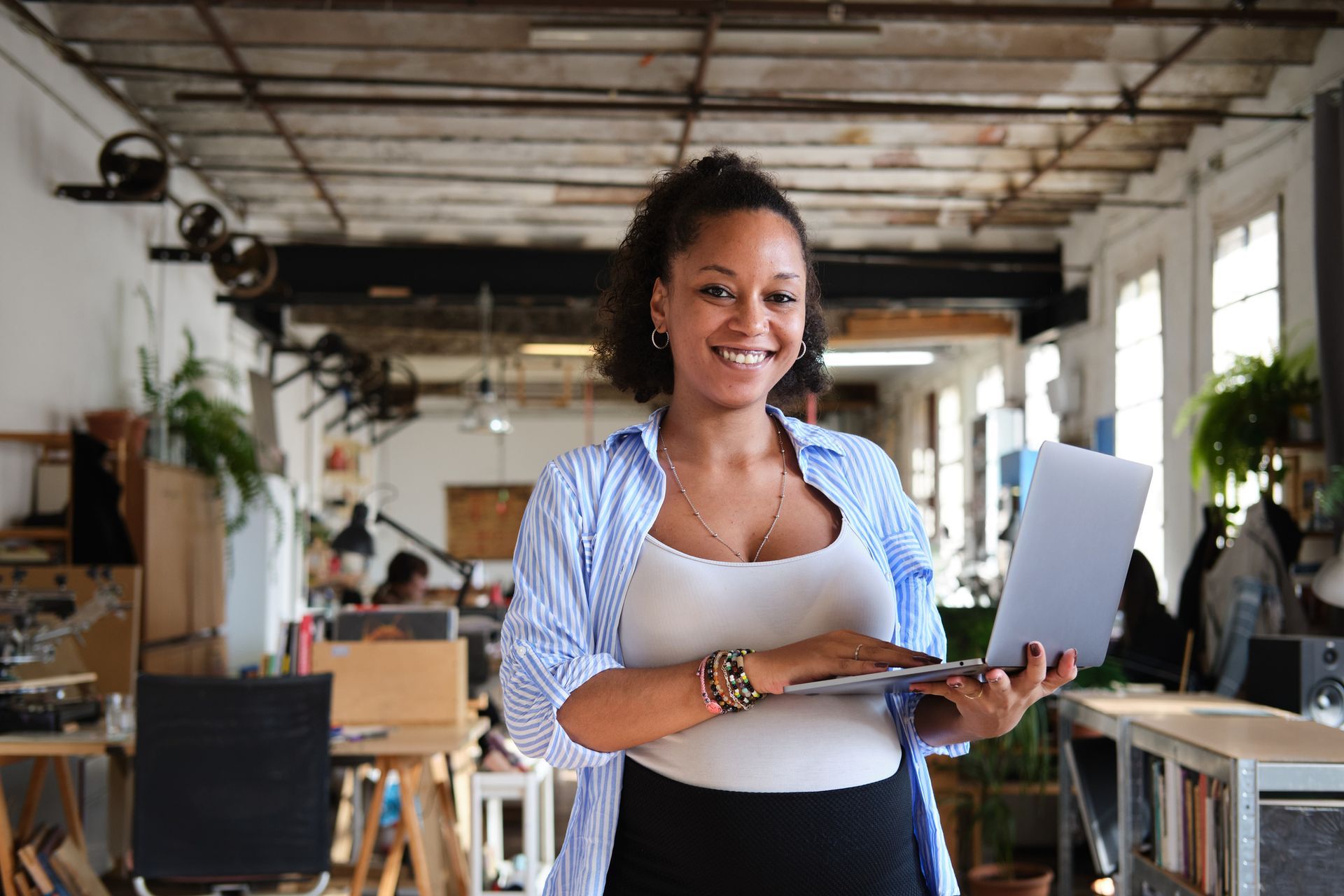 A woman is holding a laptop and a piece of paper in an office.