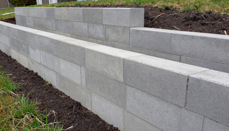 Concrete Blocks in Addis Ababa form a durable retaining wall with layered gray blocks beside landscaped soil and grass.