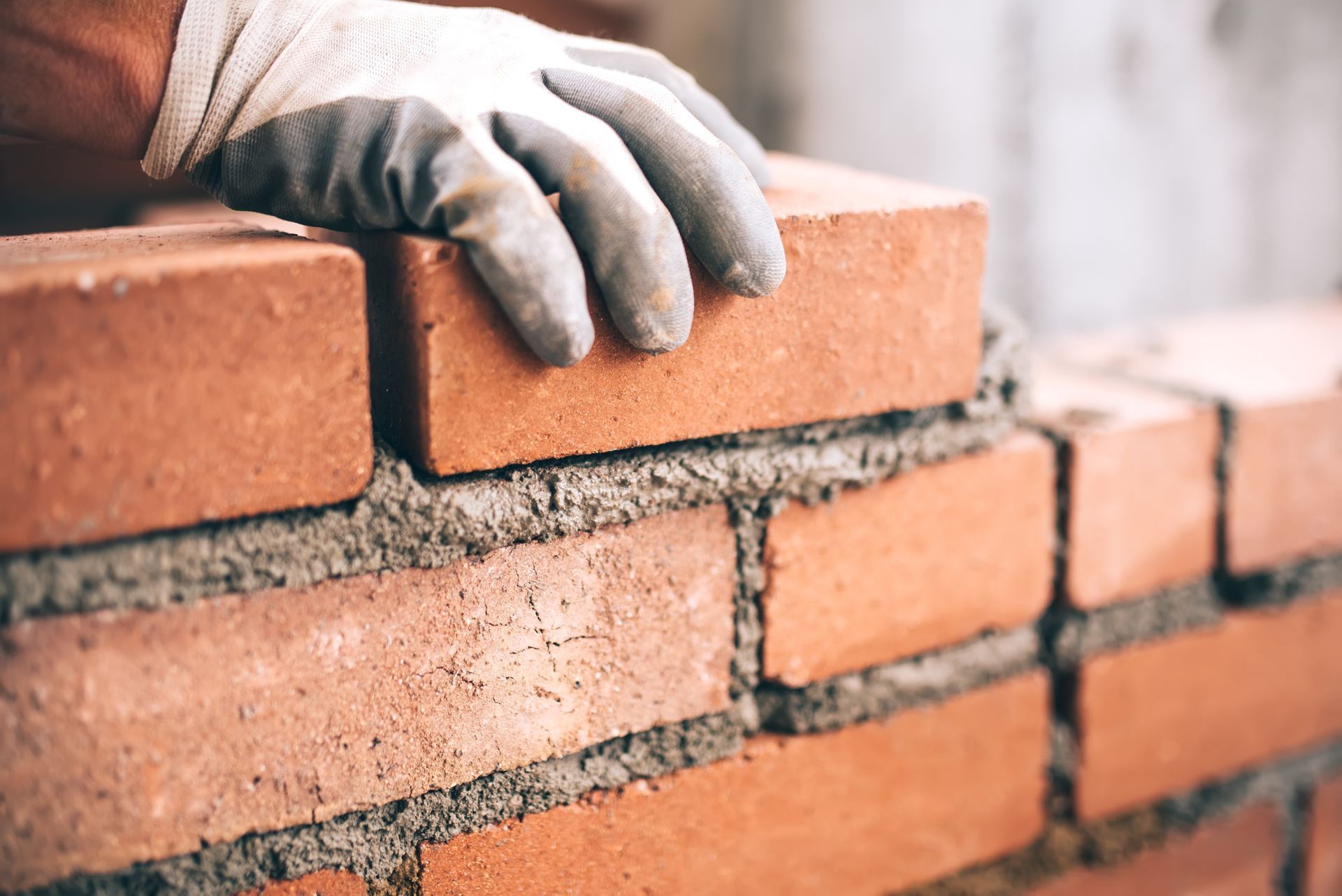 A person is laying bricks on top of a brick wall.