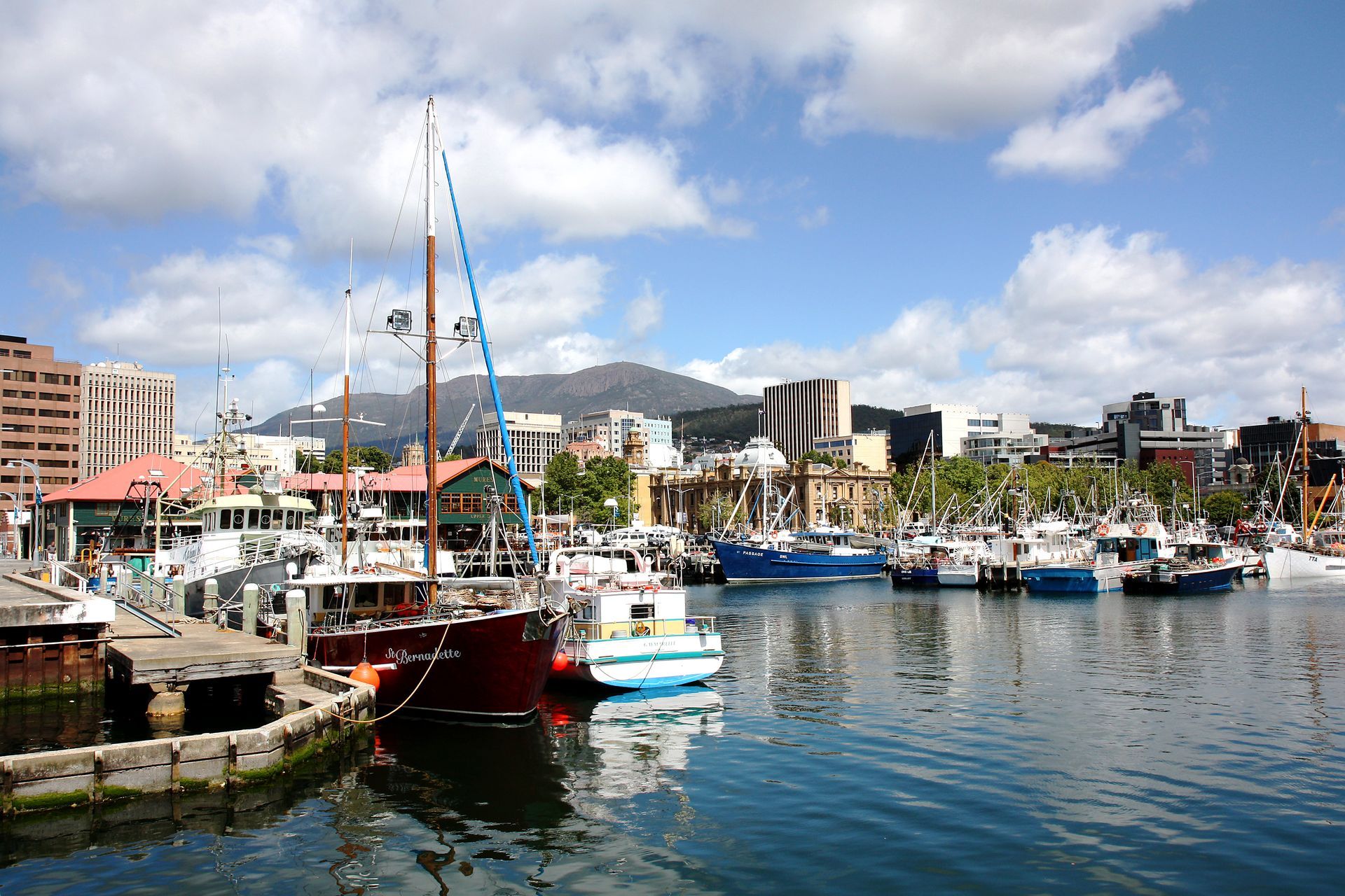 Boats are docked in a harbor with mountains in the background