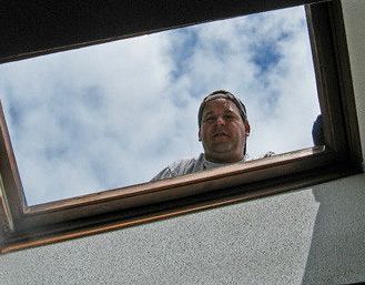 A man is looking out of a window at the sky.