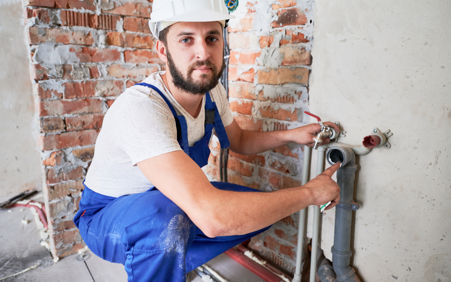 A plumber is working on a pipe in a bathroom.