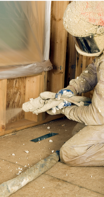 A person wearing a helmet and gloves is kneeling on the floor holding foam.