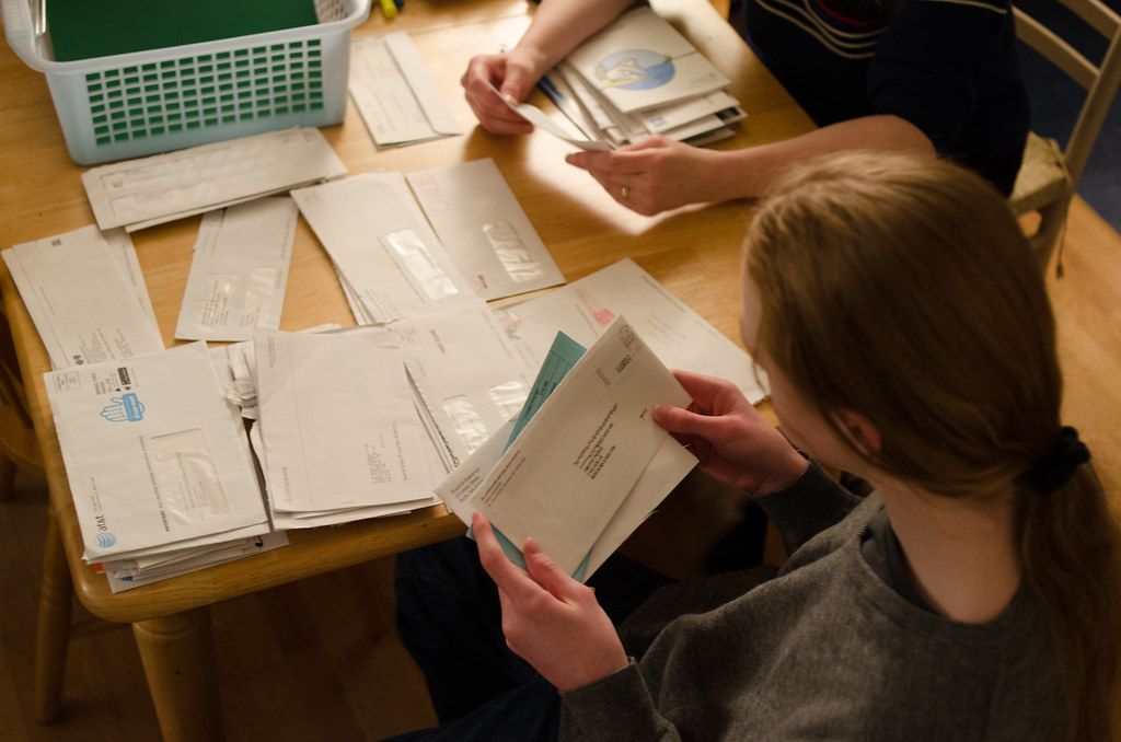 Two women are sitting at a table looking at envelopes
