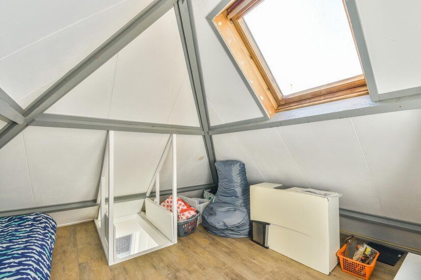 Attic room with sloped ceiling and skylight; furniture and storage bags are present.