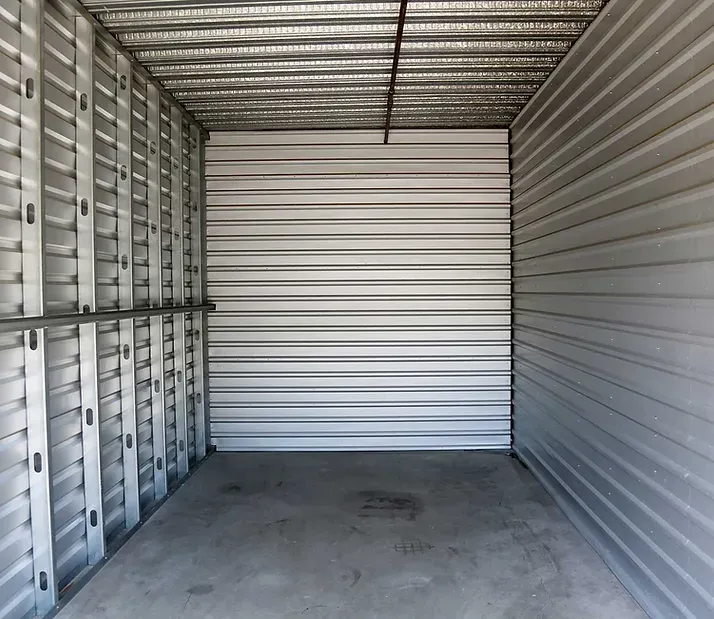 Empty, metal storage unit with a concrete floor.
