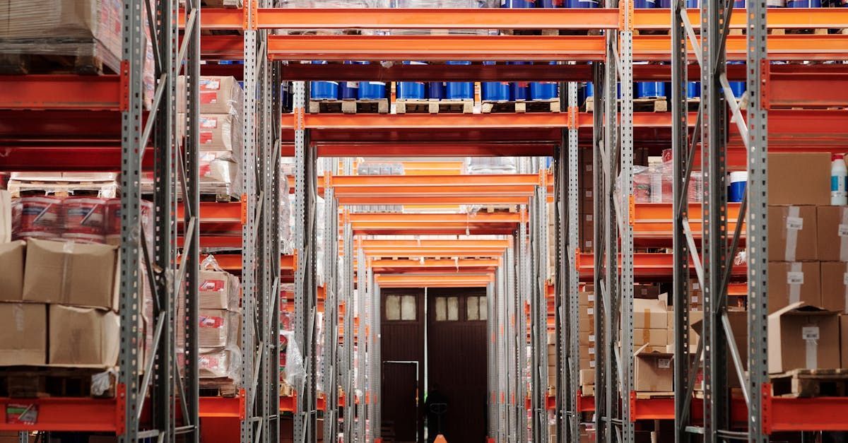 Warehouse interior with orange shelving loaded with goods. Door visible at the end of the aisle.
