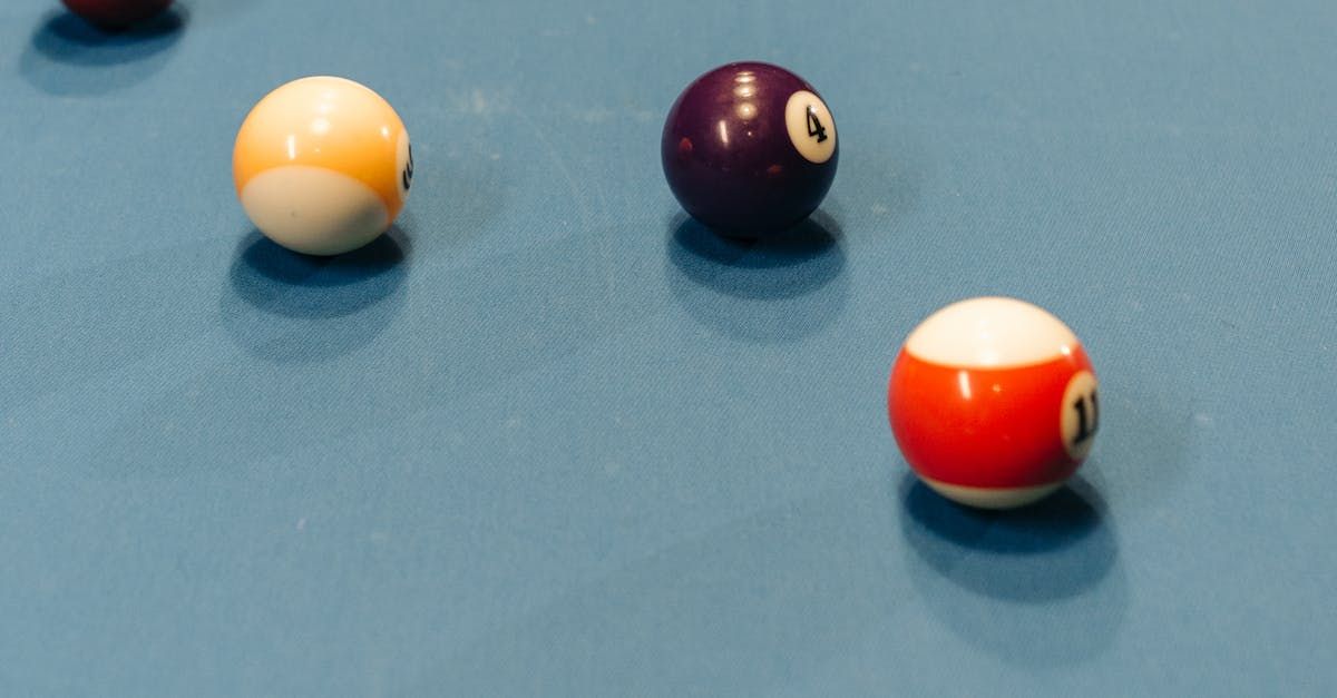 Pool balls on a blue table: yellow and white 9-ball, purple 10-ball, and red and white 11-ball.