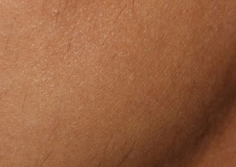Close-up of tan textured skin with a soft shadow and a curved contour