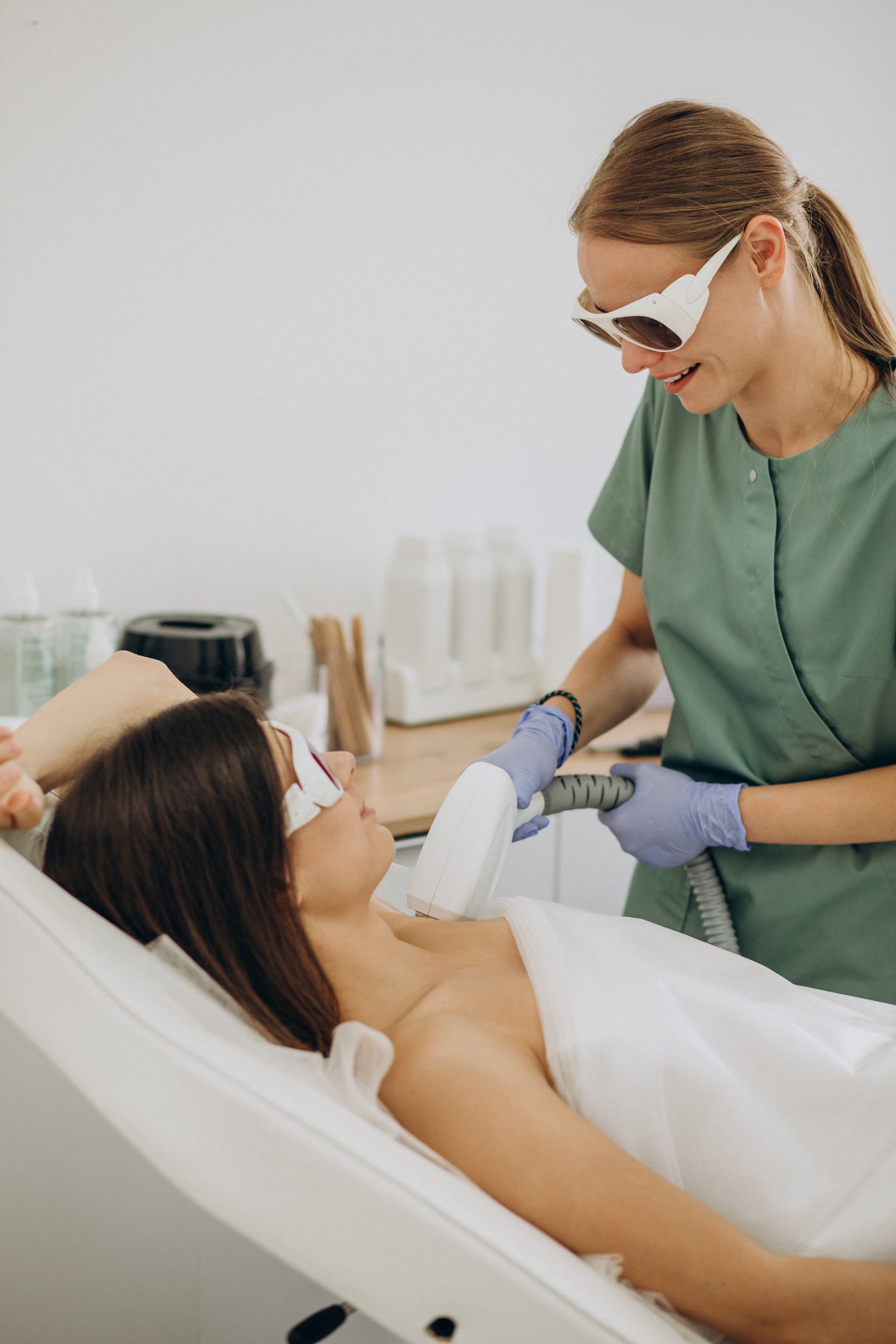 Esthetician administering facial treatment to a reclining client in a spa room