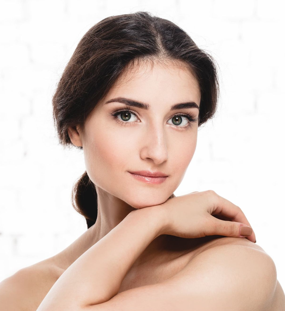 Portrait of a woman with dark hair, resting her chin on her hand against a white background
