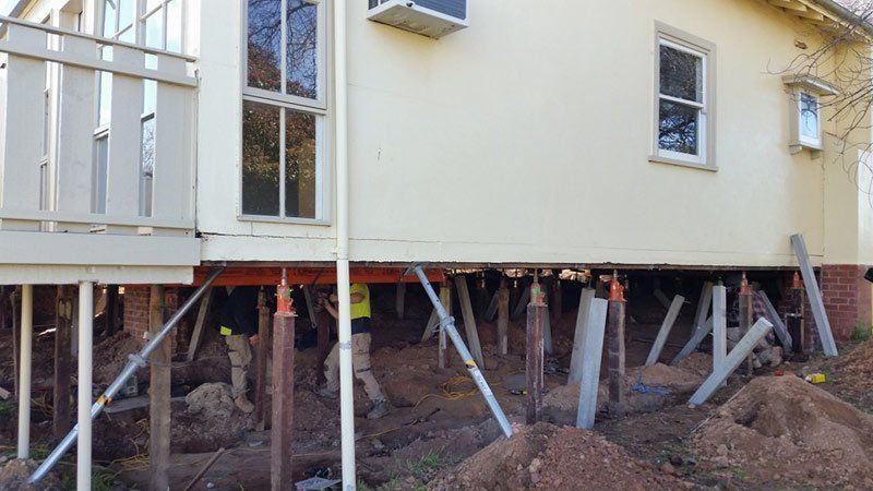 House raised on temporary support posts during foundation repair