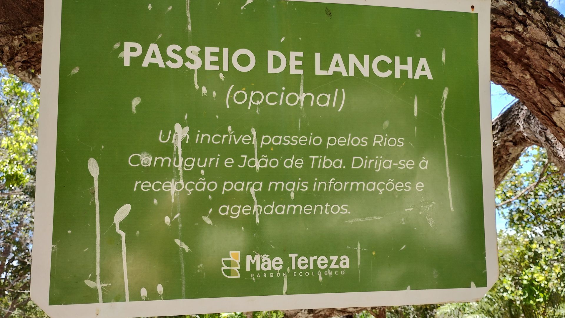 Green trail sign in Portuguese for “Passeio de lancha,” mentioning optional boat trip at Mãe Teresa.