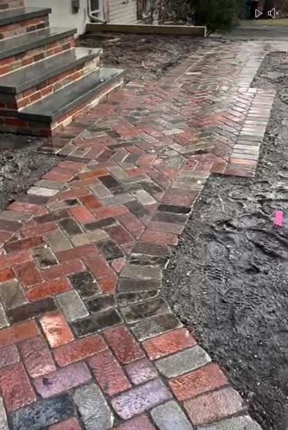 Worker placing gray stone blocks atop a low wall outdoors