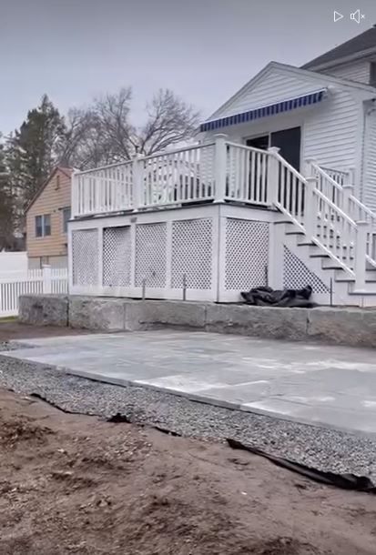 Backyard garden with stone path, log steps, mulch beds, shrubs, and a wooden fence