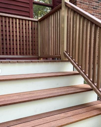 Wooden outdoor stairs with brown railings beside a brick house
