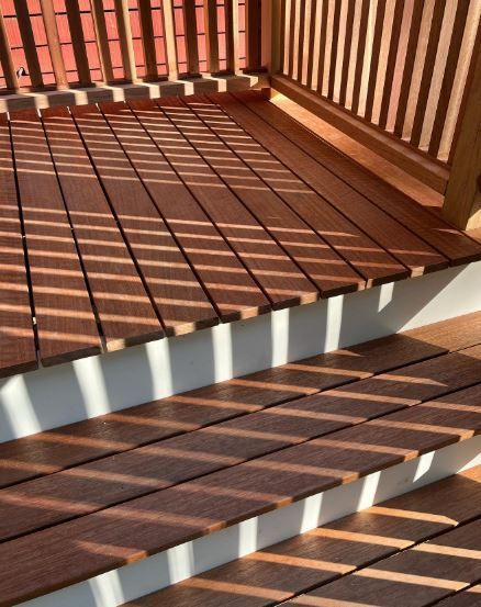 Sunlit wooden deck and stairs with striped shadows from railing slats