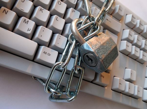Padlock and chain securing a white computer keyboard, symbolizing cybersecurity and data protection
