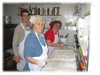 older woman and young man in the kitchen preparing meals smiling at the camera