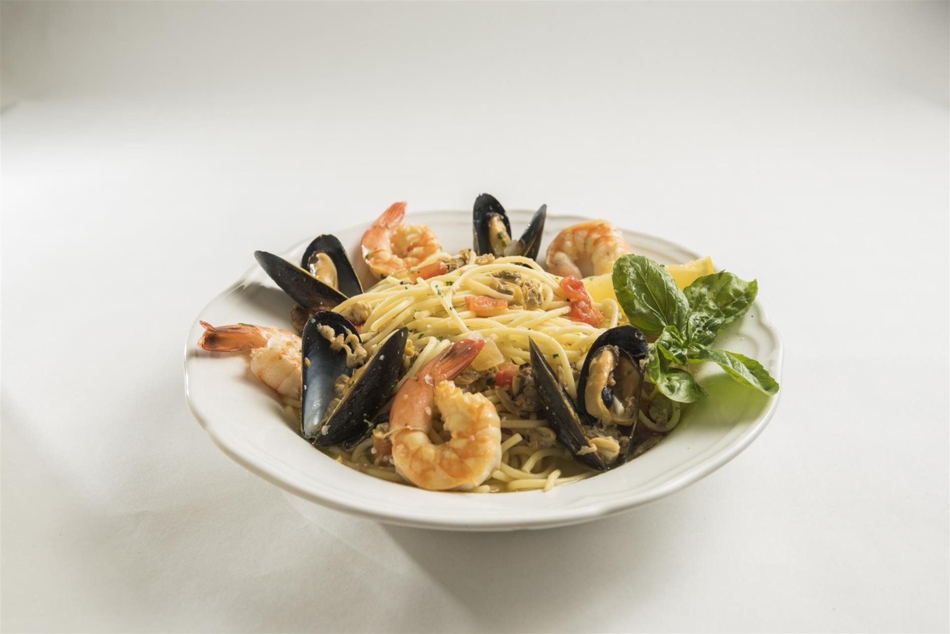 Mussels, prawns & clams with tomato, onion, lemon butter basil white  wine topped over spaghetti