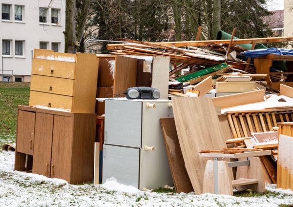 A pile of wood and appliances in a snowy field