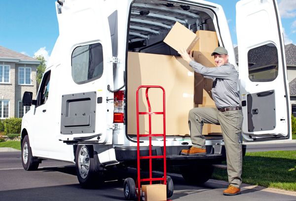 A delivery man is loading boxes into a white van.
