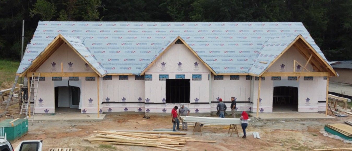 Construction site with partially built building; workers present.