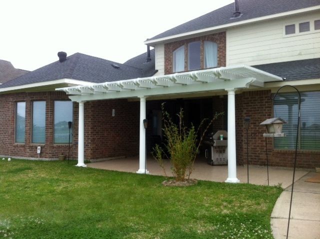 Completed pergola attached to a two-story house with brick and siding,  and green lawn