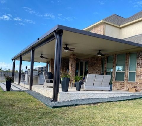 Aluminum patio cover with ceiling fans, white columns, and lounge chairs on a wooden deck in Houston, TX
