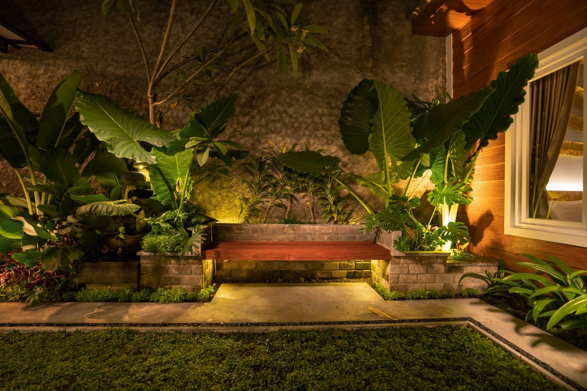 There is a bench in the middle of the garden at night.