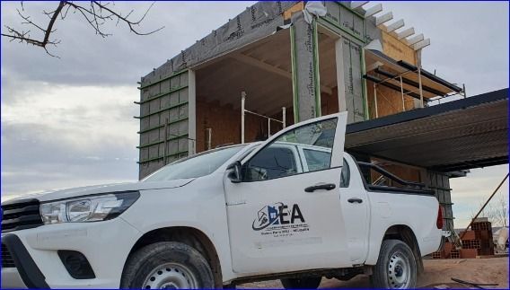 Camioneta blanca con el logotipo de la DEA estacionada cerca de un edificio parcialmente construido.