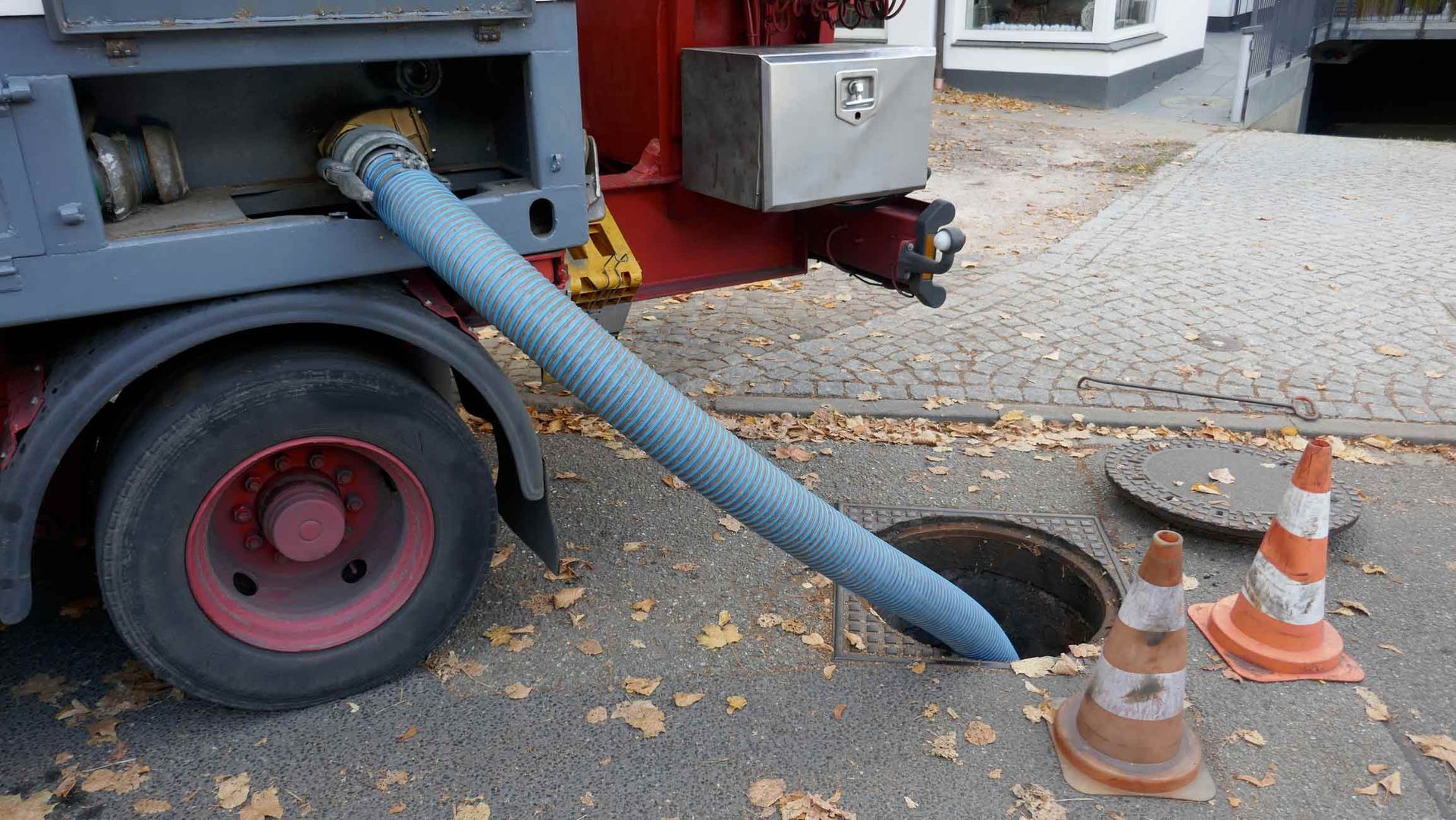 A Truck Is Pumping Water Into A Manhole On The Side Of The Road — Peoria, IL — Rooter-Matic Sewer Drain and Septic