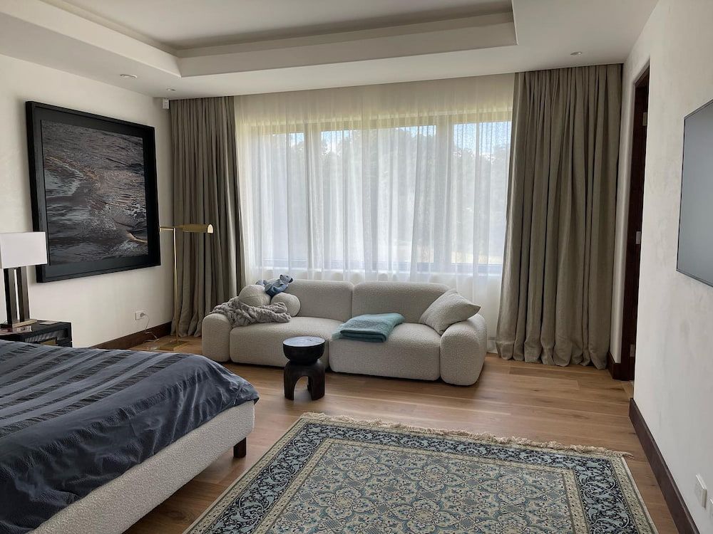 Bedroom With a White Couch, Large Window With Sheer Curtains, Hardwood Floors, and a Rug — BlindDESIGN in Mullumbimby, NSW