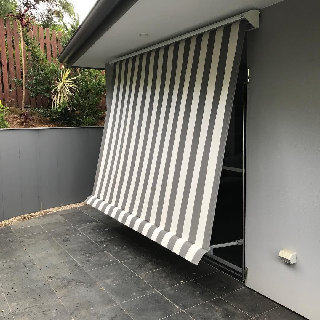 Striped Gray and White Awning Extended Over a Patio With a Sliding Glass Door — BlindDESIGN in Byron Bay, NSW
