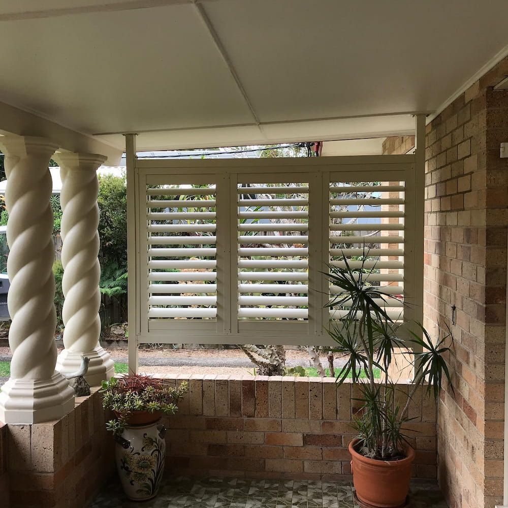 Cream Shutters on a Porch With Brick and Decorative Columns, With Potted Plants — BlindDESIGN in Mullumbimby, NSW