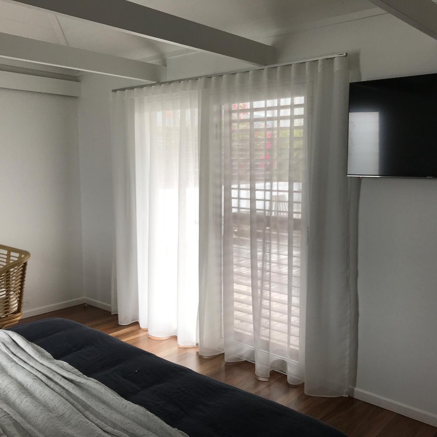 Bedroom With Sheer White Curtains Over a Door, and a Tv Mounted on the Wall — BlindDESIGN in Lismore, NSW
