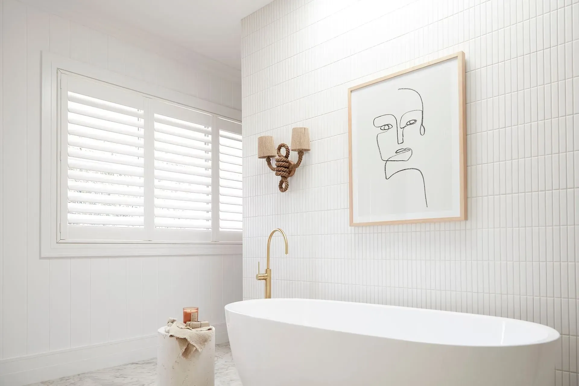 White Bathroom With a Freestanding Tub, Gold Faucet, and Abstract Art on a Tiled Wall — BlindDESIGN in Byron Bay, NSW