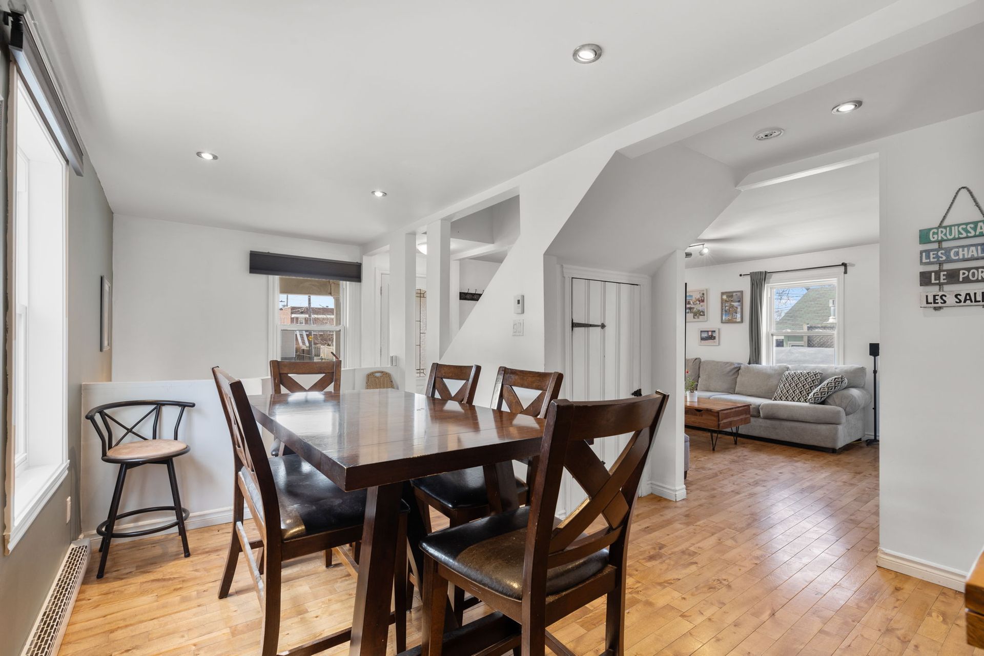 Salle à manger avec table et chaises en bois, parquet et vue sur le salon.