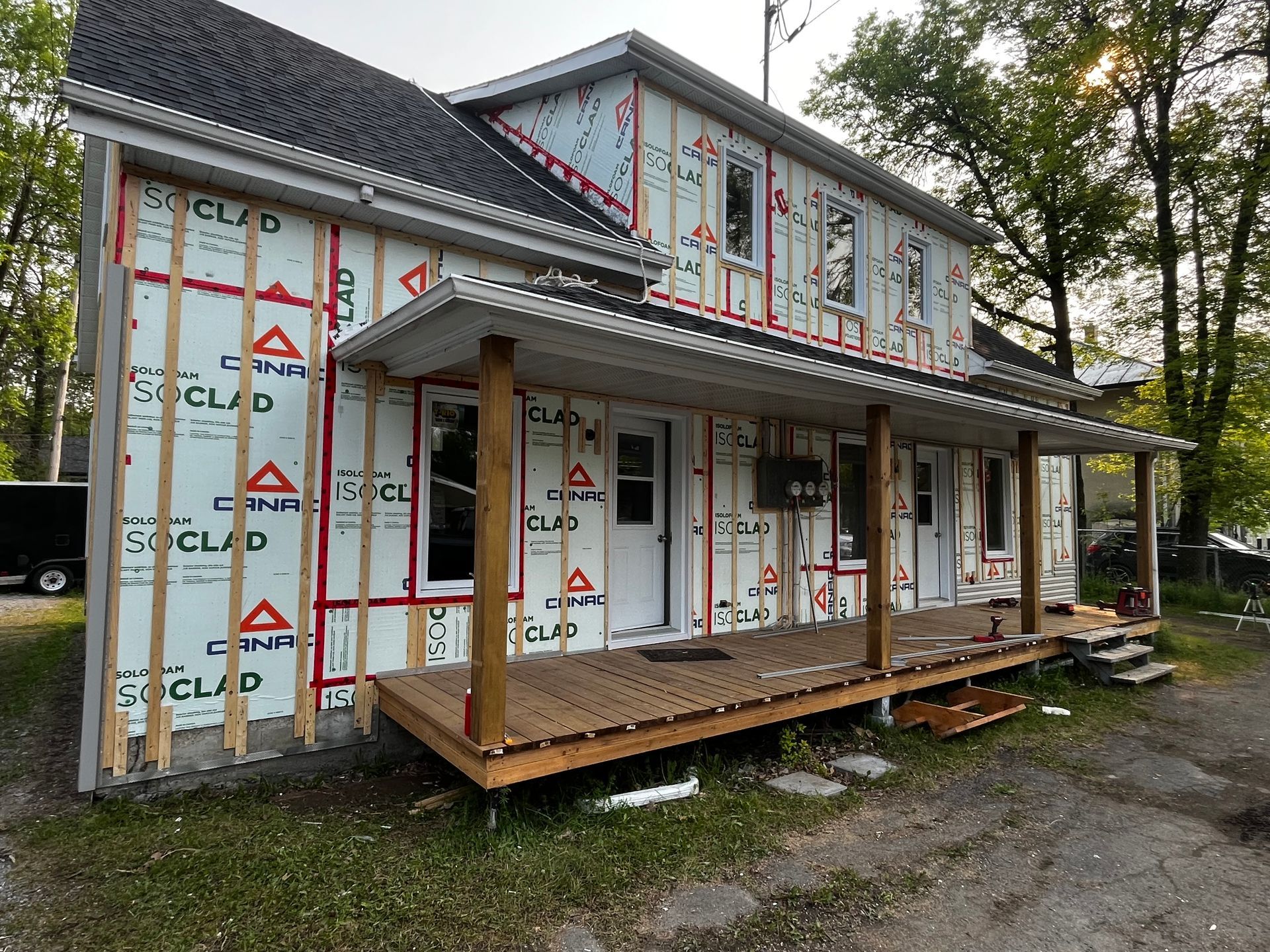 Maison en rénovation avec nouveau revêtement extérieur, porche avec terrasse en bois.
