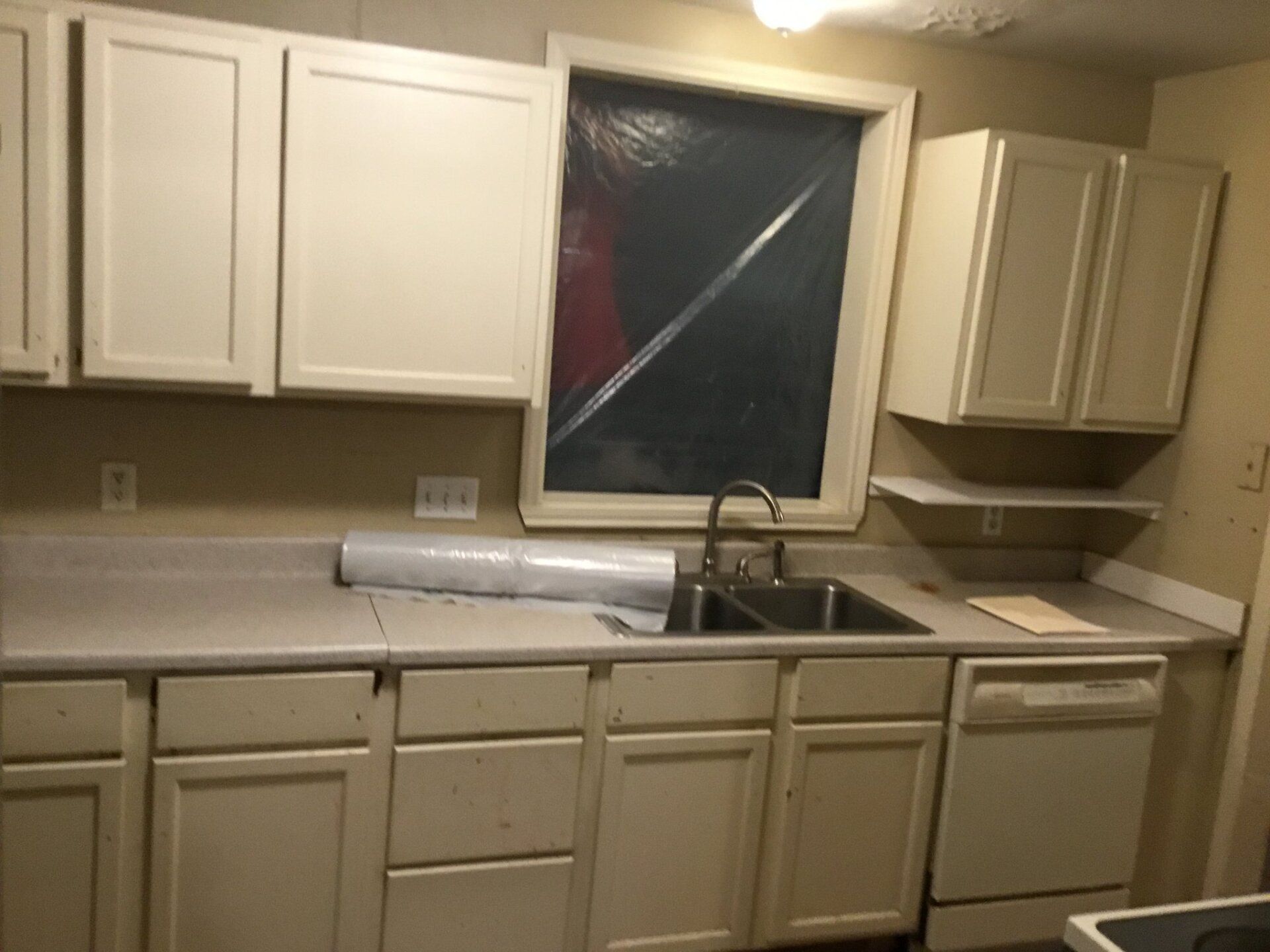 A kitchen with white cabinets a sink and a window